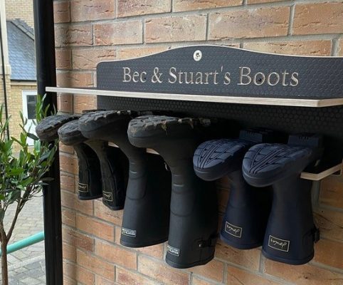 Brown Wooden welly rack with a shelf hung on a porch outside, holding wellingtonsa house