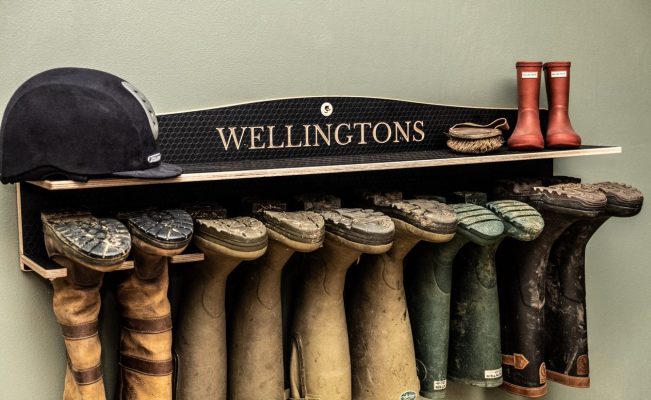 A 5 pair wall mounted wellington Rack engraved with Wellingtons, shown holding quality wellies and country boots