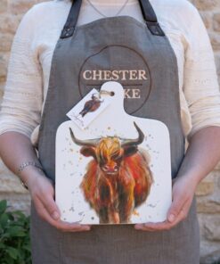 a person in a chester & Cooke apron holding a mini highland cow chopping board